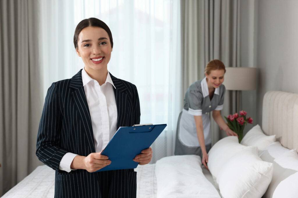 Hotelmanagerin überprüft Zimmerreinigung mit Mitarbeiterin